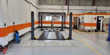 Empty vehicle inspection bay with a hydraulic lift in a clean garage.
