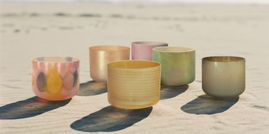 Colorful glass bowls casting shadows on sand.