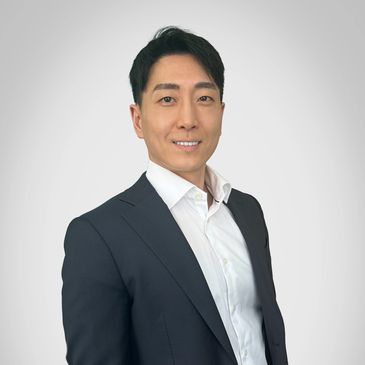 Professional portrait of a man in a suit with a white shirt against a neutral background.