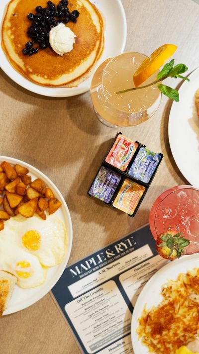 breakfast items on table including eggs, potatoes, pancakes, hashbrowns, and cocktails