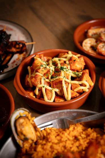 Bravas - Double fried potatoes with fiery tomato sauce, sweet paprika, and aioli.