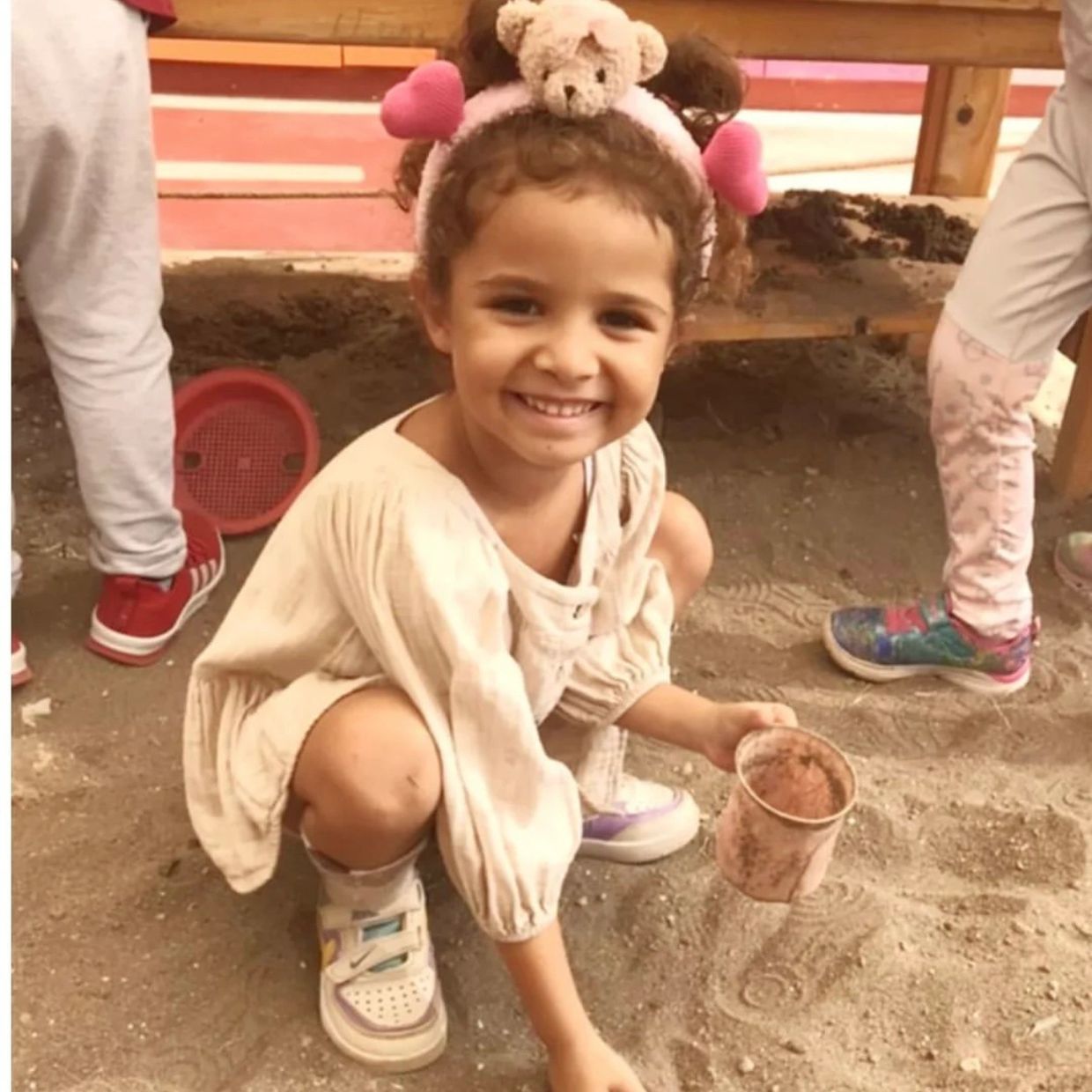 A little girl with a big beautiful smile is playing in the sand