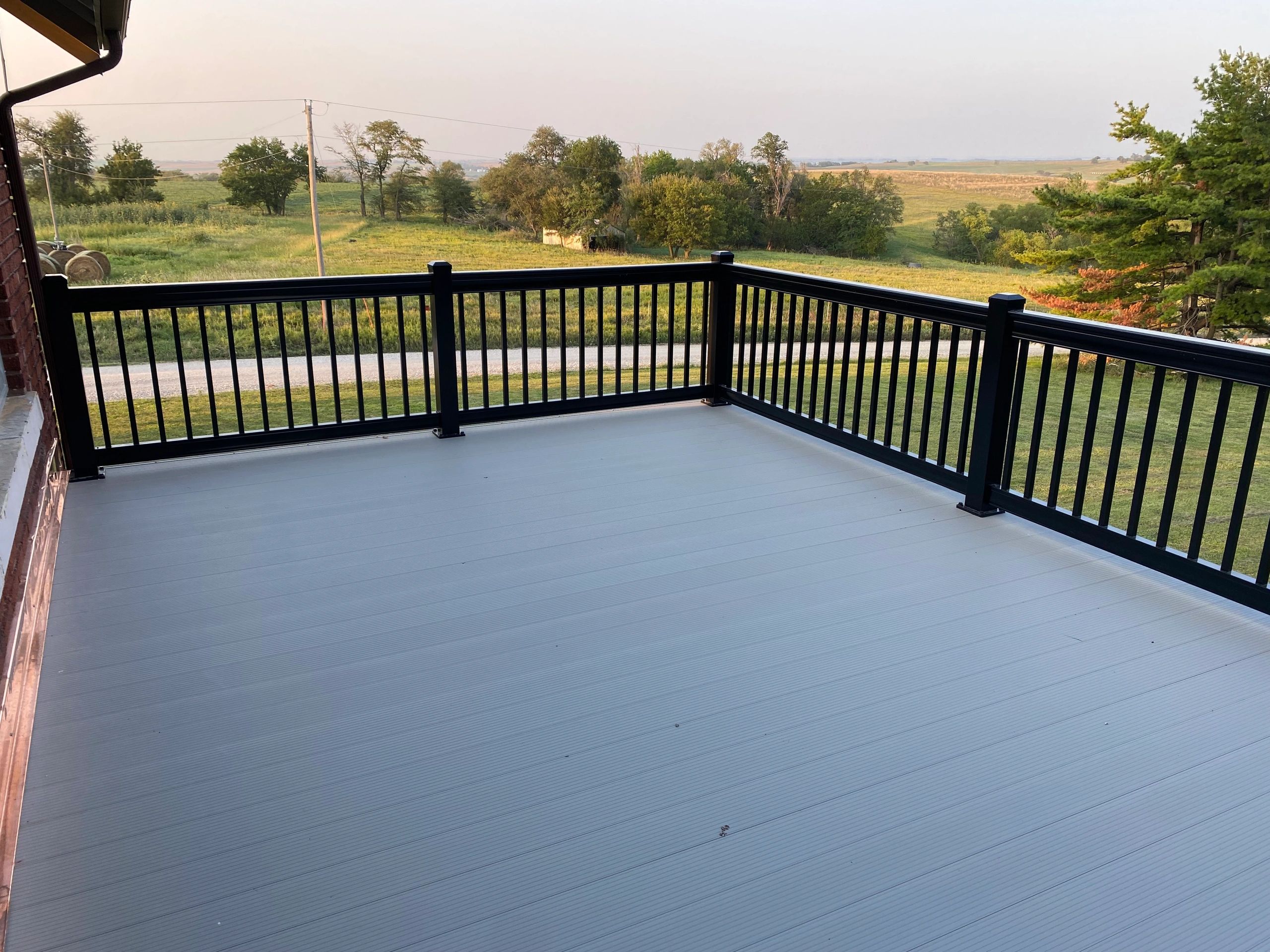 Spacious outdoor deck with black railing and countryside view.