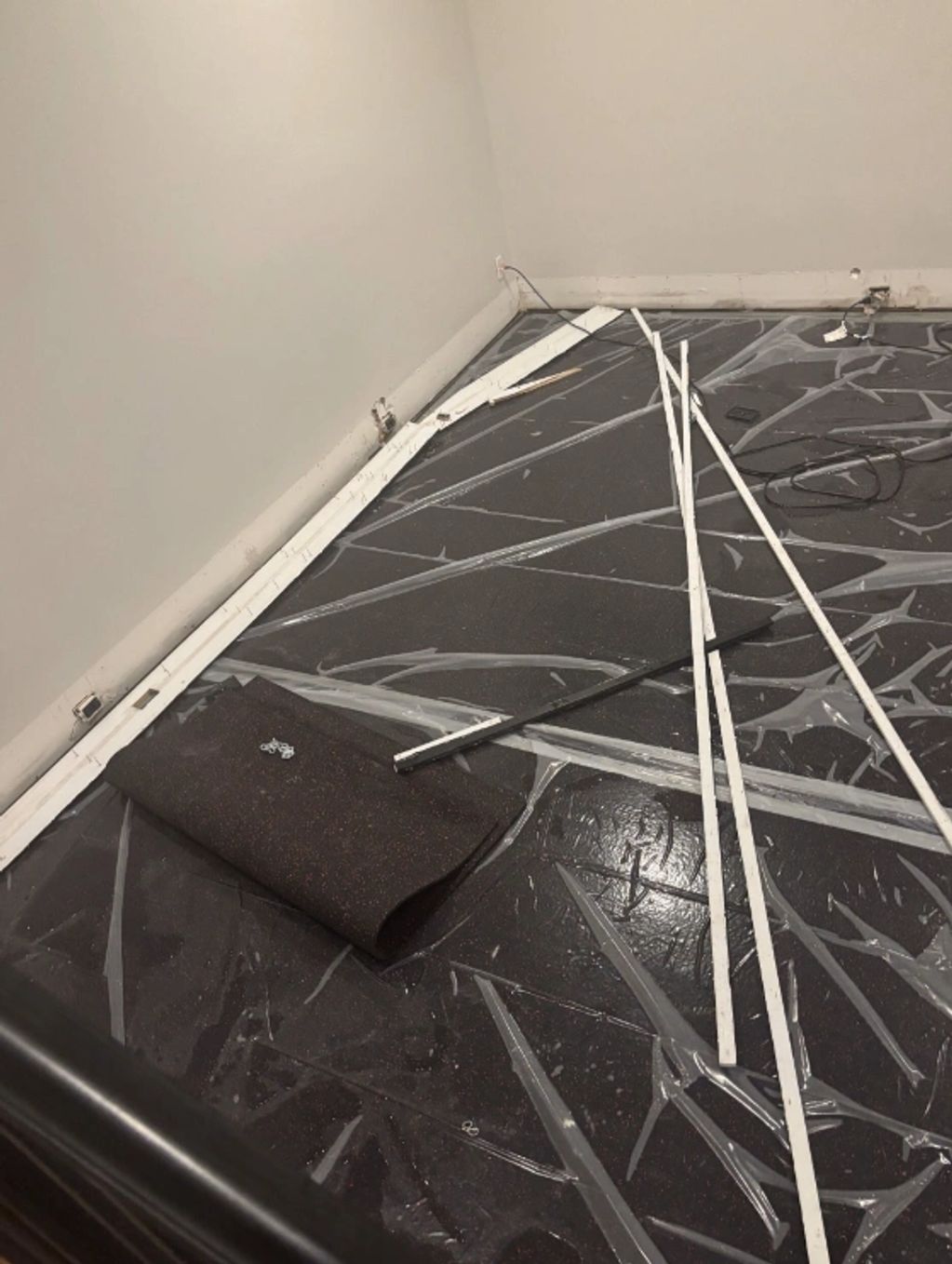 Room under renovation with protective floor covering and scattered construction materials.