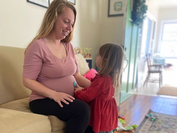Mom and toddler daughter in birth center during prenatal visit sitting on couch 