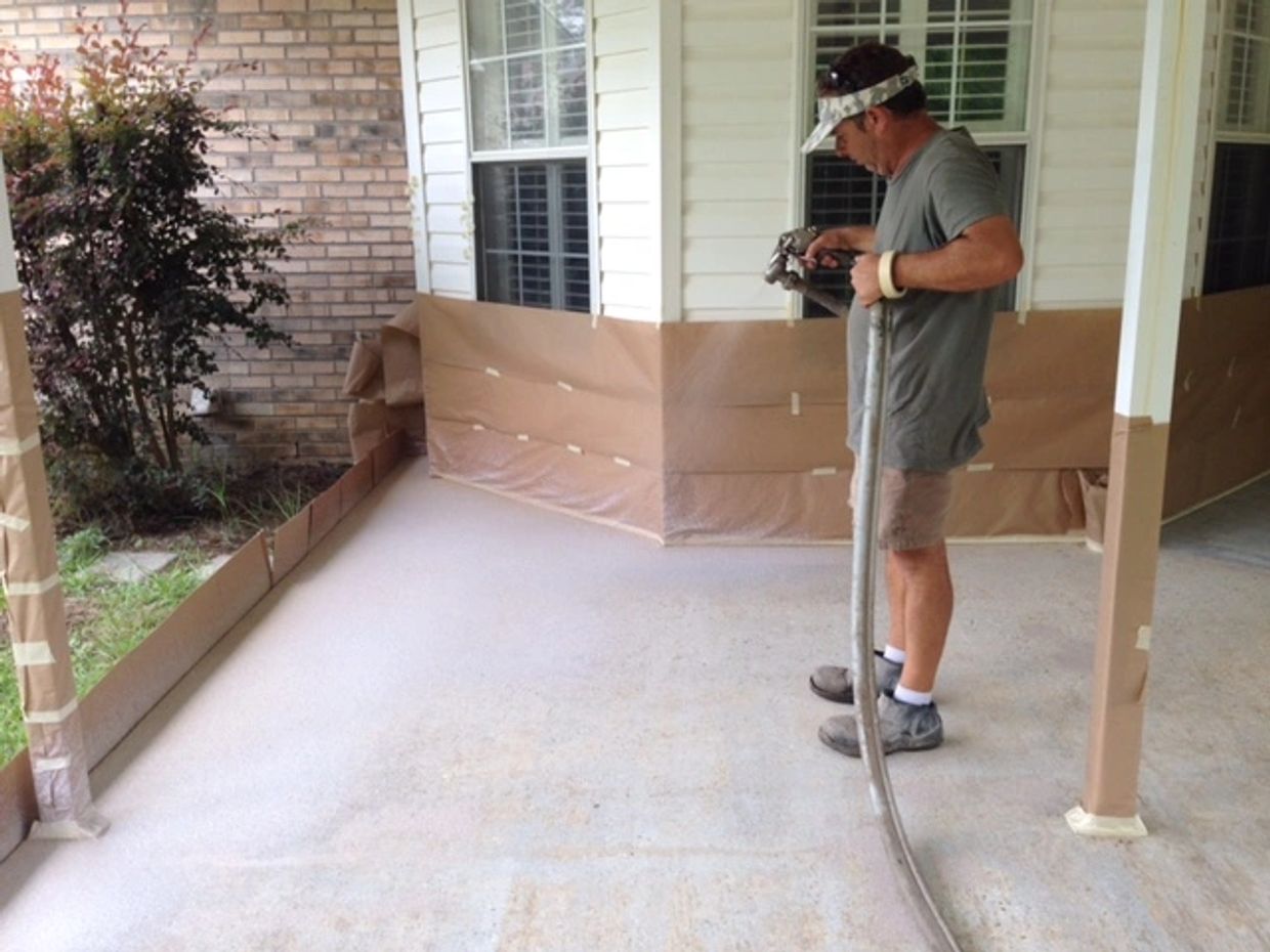 Man spraying primer or paint on porch floor