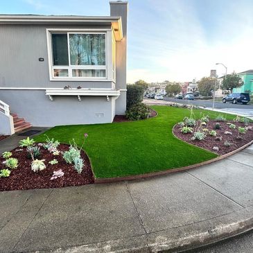 Neatly landscaped front yard with green grass and mulch beds by a residential house.