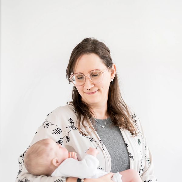 Nicole, a Calgary Birth and Postpartum Doula, gently holding a newborn during a home visit.