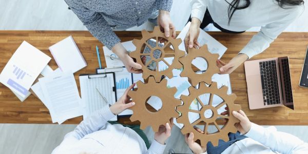Team holding interlocking cardboard gears above a desk.