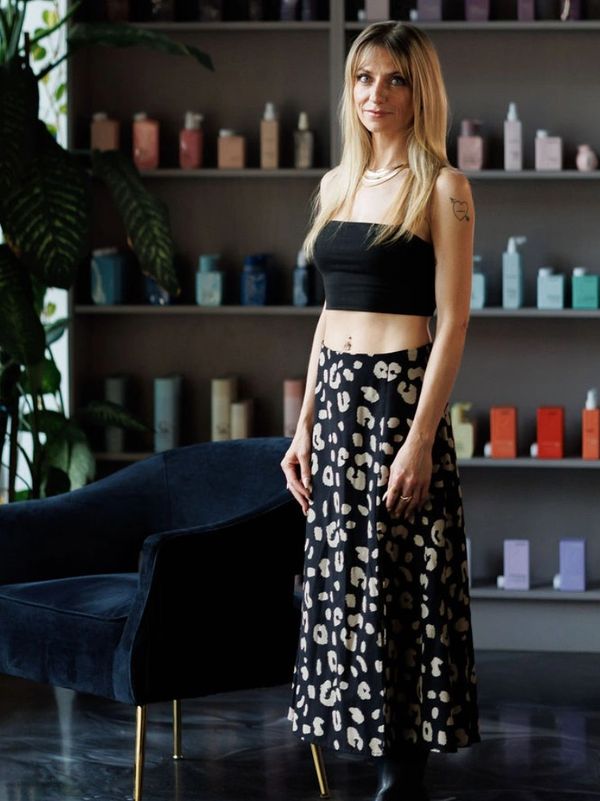 Woman standing in a stylish salon with plants and beauty products.