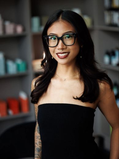Smiling woman with glasses and dark hair wearing a black strapless top.