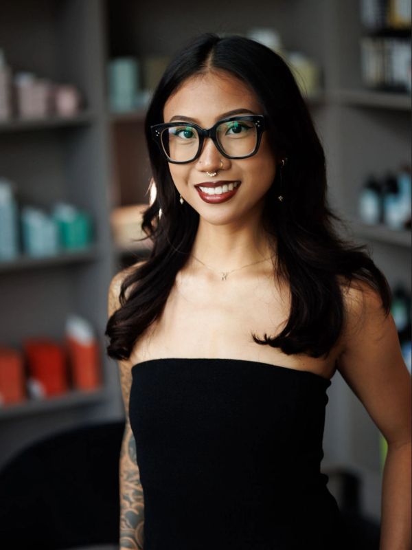 Smiling woman with glasses and dark hair wearing a black strapless top.