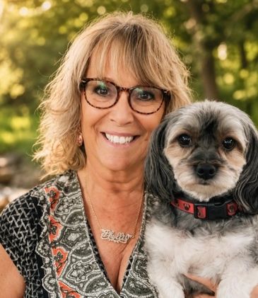 Woman smiling with her dog outdoors.