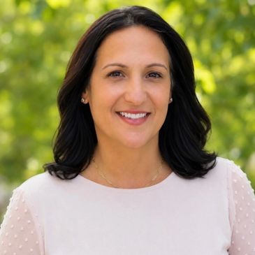 Smiling woman outdoors with blurred green background.