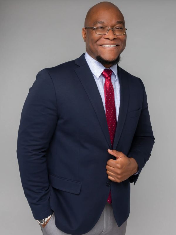Confident man in navy blazer and red tie smiling.