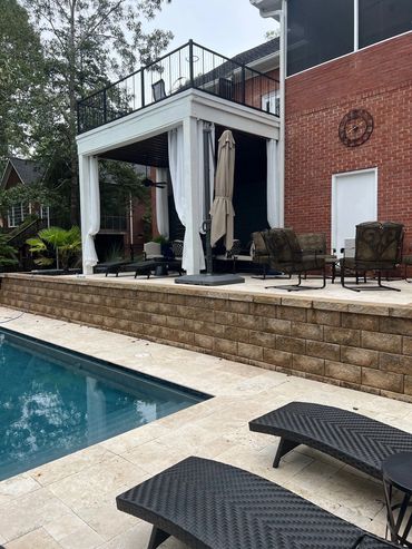 Backyard pool area with lounge chairs and covered patio.