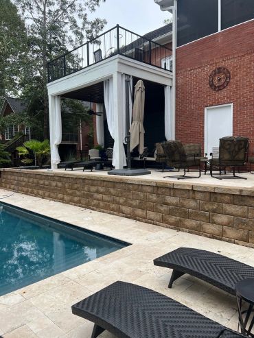 Backyard pool area with lounge chairs and covered patio.