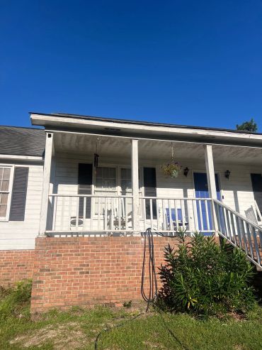 Front porch of a white house with blue door and brick steps.