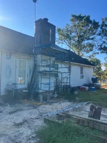 House exterior with chimney under construction and scaffolding.