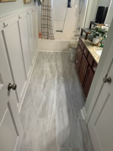 A clean bathroom with marble-style tile flooring and wooden cabinets.
