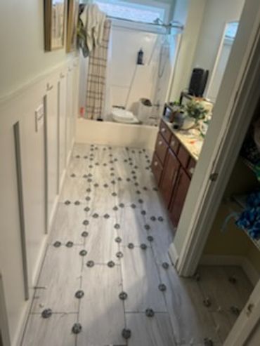 Bathroom under renovation with tiles being installed on the floor.
