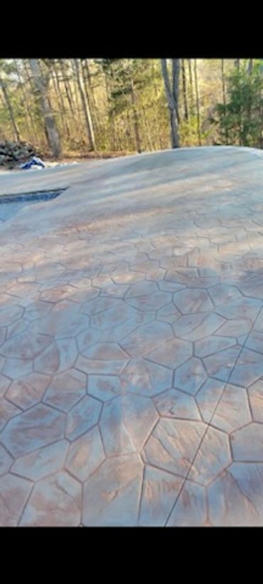 Stamped concrete patio with a hexagonal pattern in an outdoor wooded area.