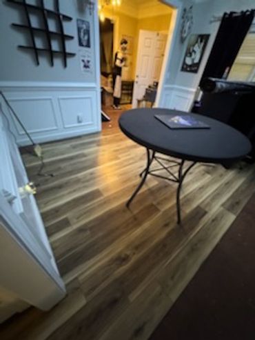 Room with wood flooring, a round table, and a mannequin in the background.