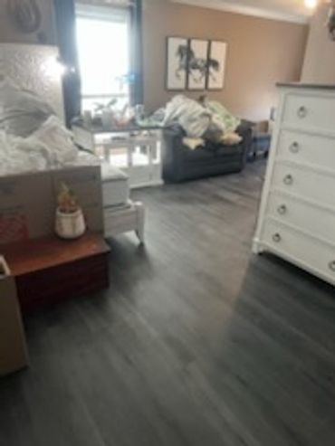 Cozy bedroom with white furniture and dark wood flooring.
