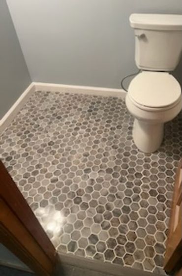 Bathroom with hexagonal tile flooring and white toilet.