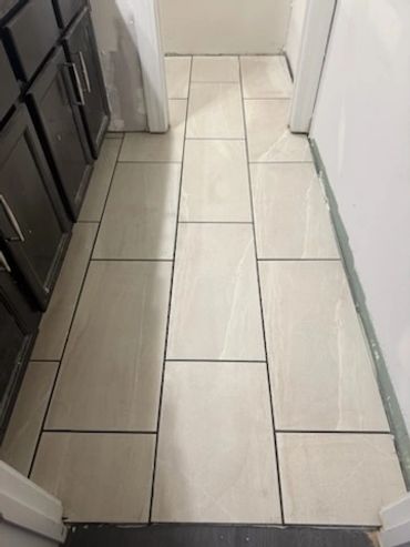 Newly installed beige floor tiles in a narrow kitchen or hallway area.