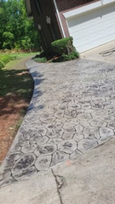Stamped concrete driveway with a hexagonal pattern near a garage.