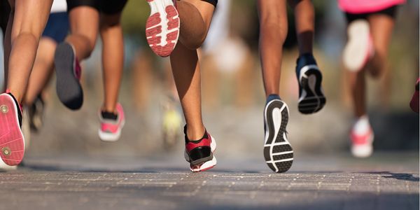 Close-up of runners' feet in motion during a race on a paved road.