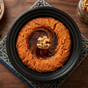 A plate of muhammara garnished with walnut.