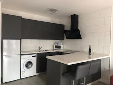 Cocina moderna con electrodomésticos integrados y barra desayunadora.