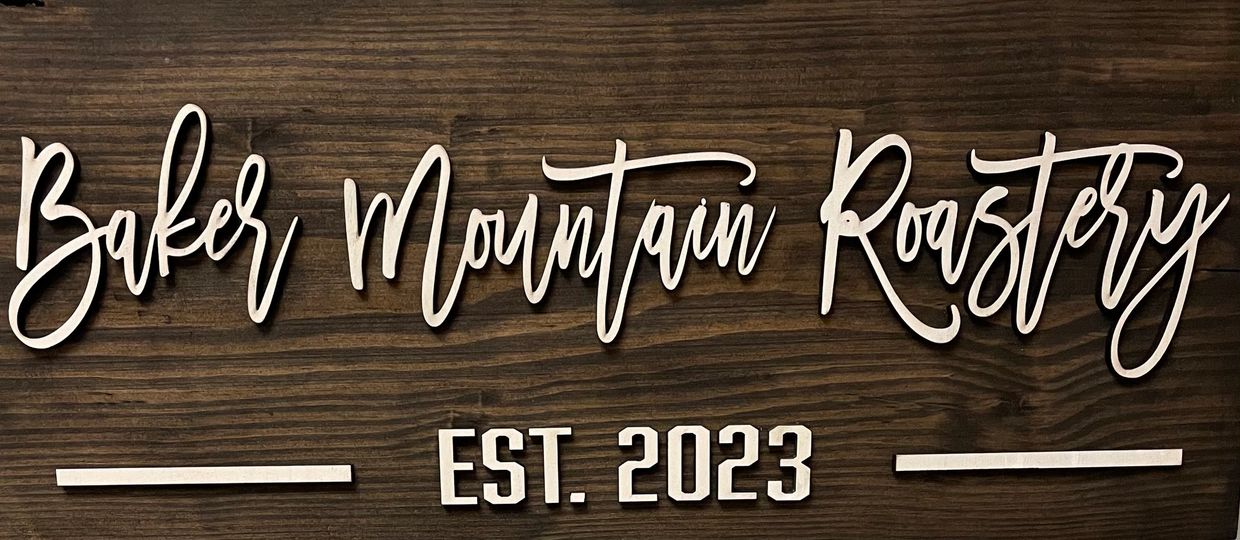 Wooden sign reading 'Baker Mountain Roastery EST. 2023' in elegant script.