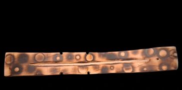 Ancient bronze strip with circular indentations.