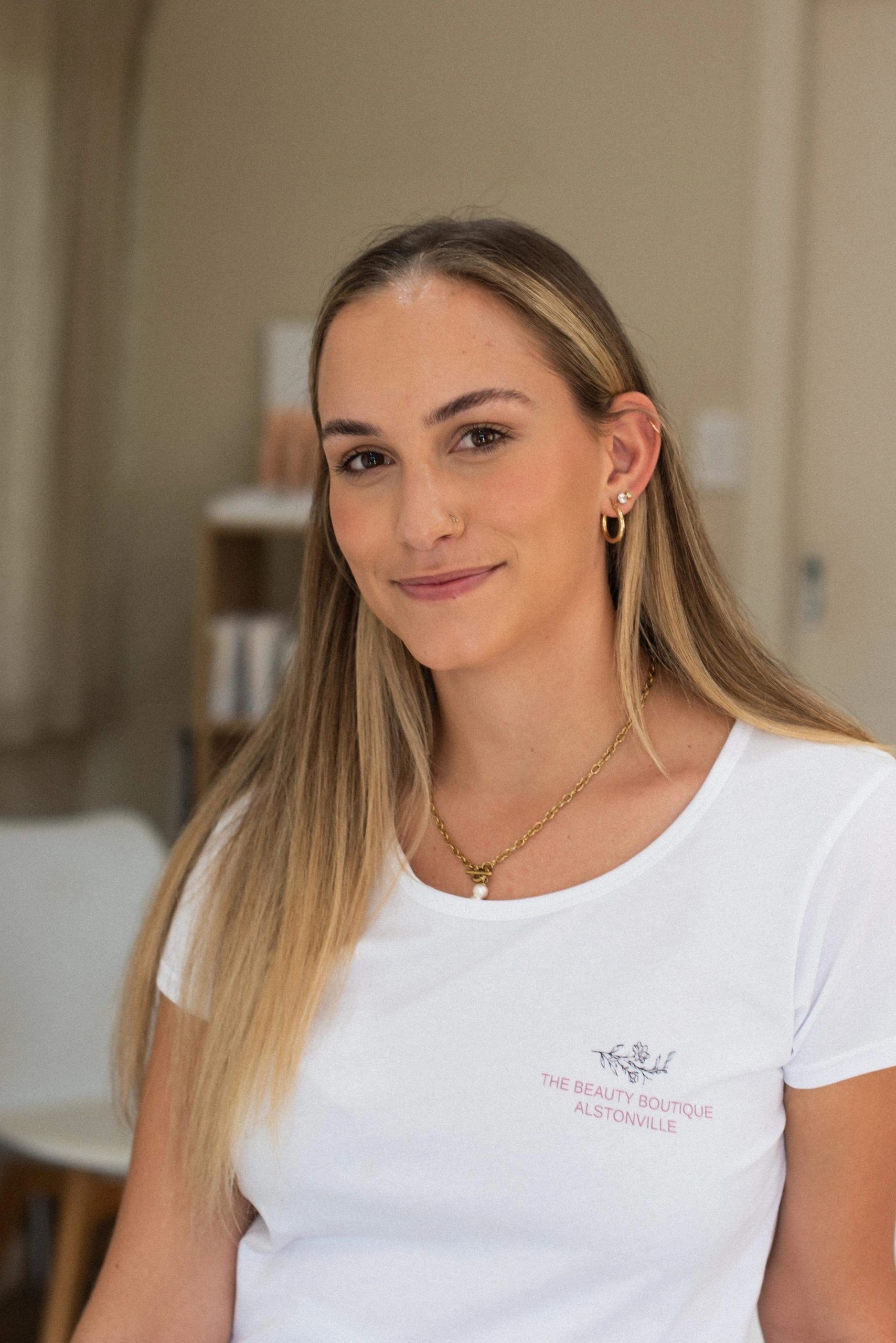 Smiling young woman with long blonde hair in a white tee.