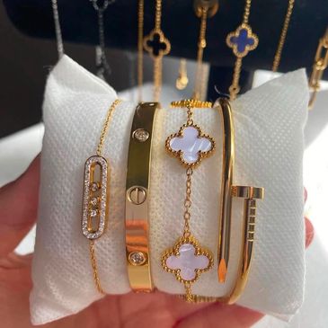 Elegant gold and diamond bracelets displayed on a white cushion.