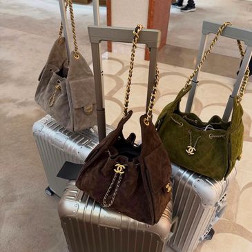 Three designer handbags on silver suitcases in a chic setting.