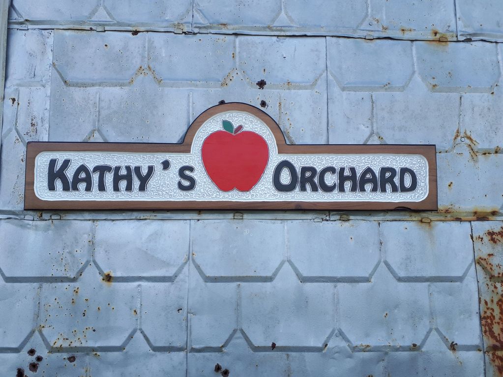 This sign shows a red apple between the name Kathy and the word Orchard.