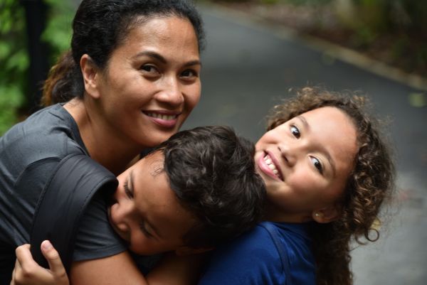 Happy family hugging outdoors on a path.