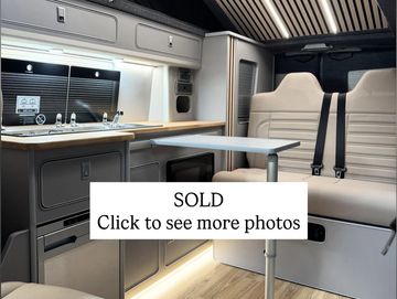 Interior of a modern camper van with a kitchenette and seating area.