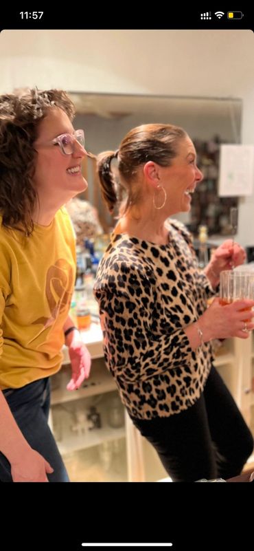 Two women laughing and enjoying a moment indoors.