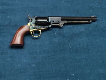A classic revolver with a wooden handle on a blue fabric background.