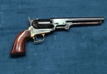 A vintage revolver with a wooden handle on a blue surface.