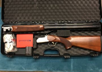 Disassembled shotgun in a protective foam case with accessories.