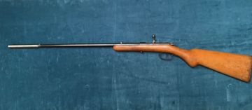 A classic wooden-stock rifle with a long barrel placed on a blue fabric.