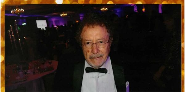 Elderly man in tuxedo at formal event.