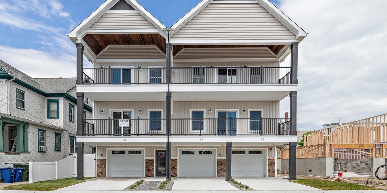 Modern three-unit townhouse with balconies and garages.