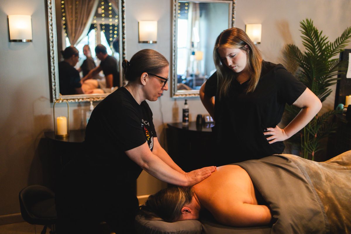 Instructor teaching a student massage technique in a Spa One treatment room